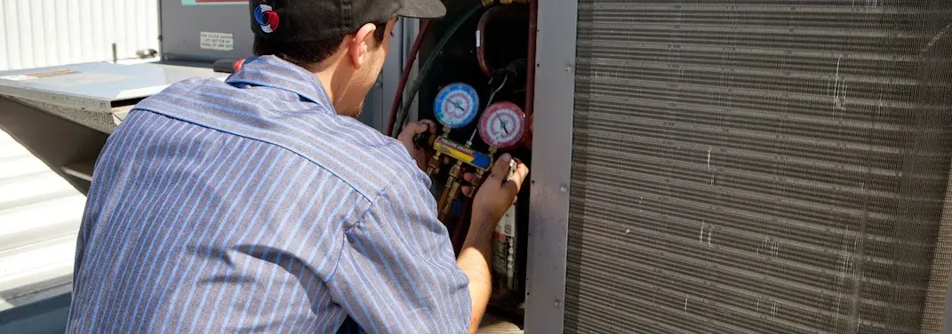 HVAC technician servicing a condenser unit in Windsor